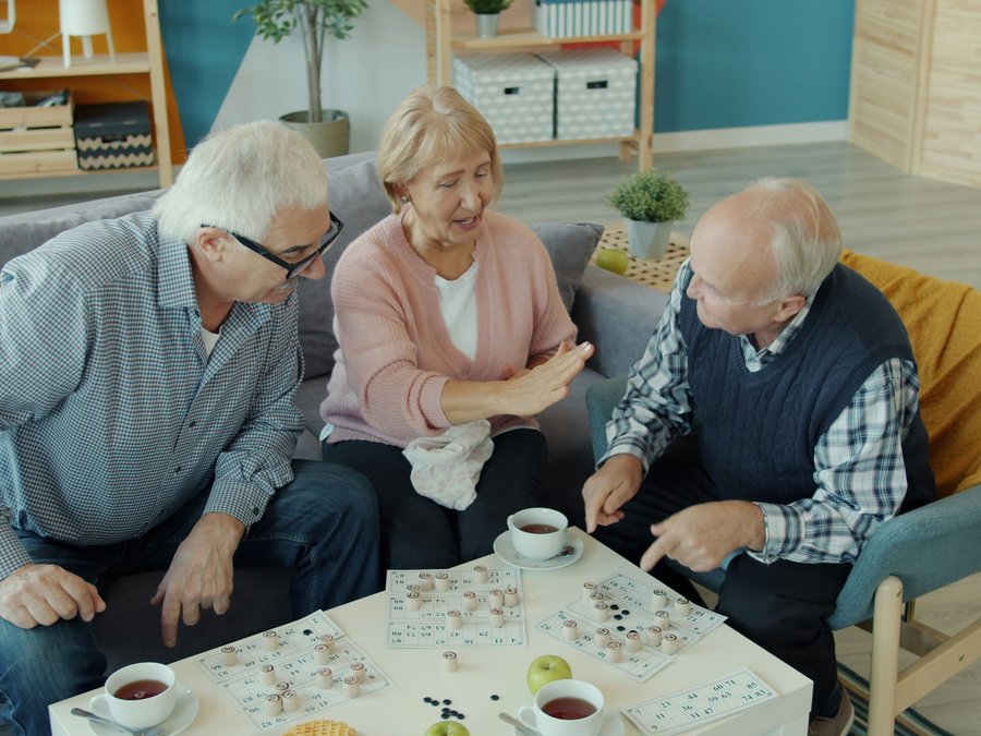 Three older adults playing a number game together at home